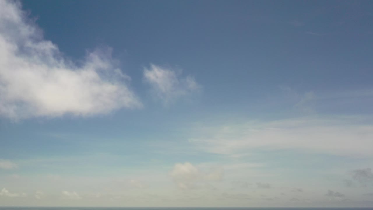 Opening frame of a blue Los Cabos sky with a large white cloud entering from the upper left, softer cloud haze near the bottom, and no visible people.