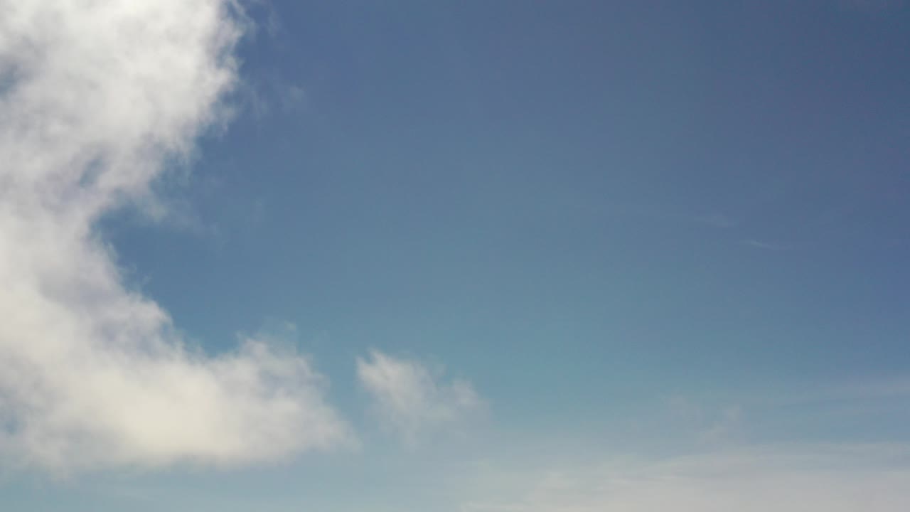 Los Cabos blue sky with a broad white cloud mass along the upper left and lower left edges, no visible people.