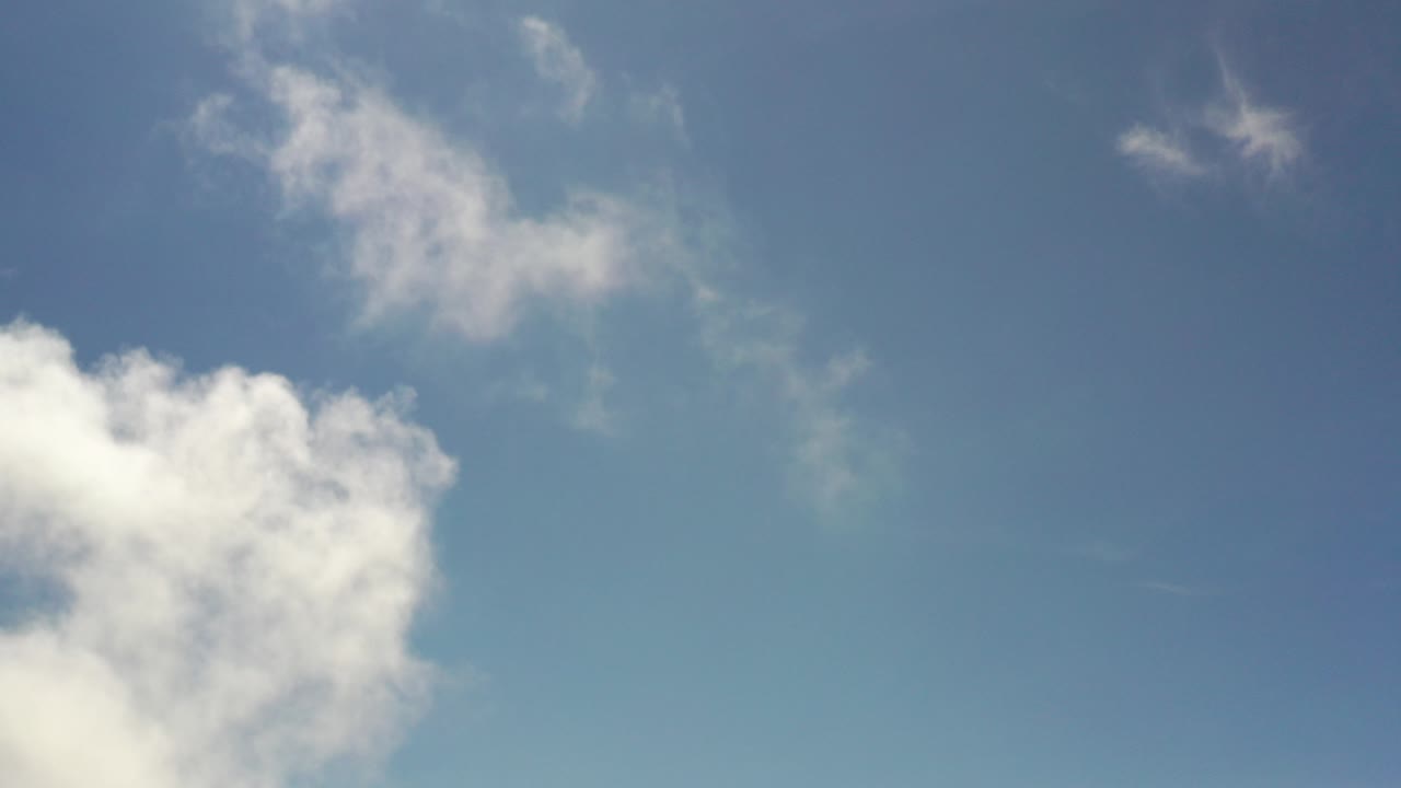 Opening frame of a Los Cabos, Mexico sky view, with white cloud mass low on the left and thin wisps near the top, no visible people.