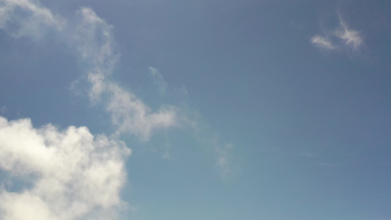 Blue sky with white clouds in the lower left and wispy clouds above.