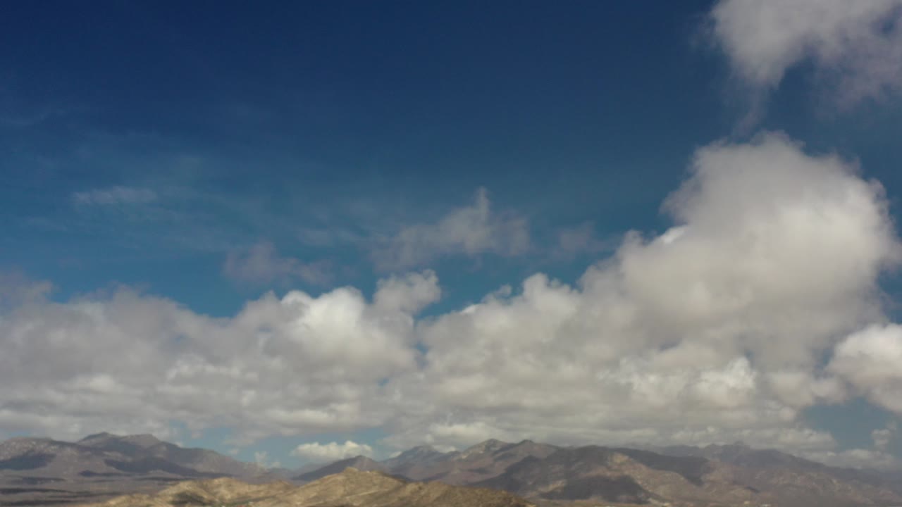 White clouds over distant mountains and blue sky.