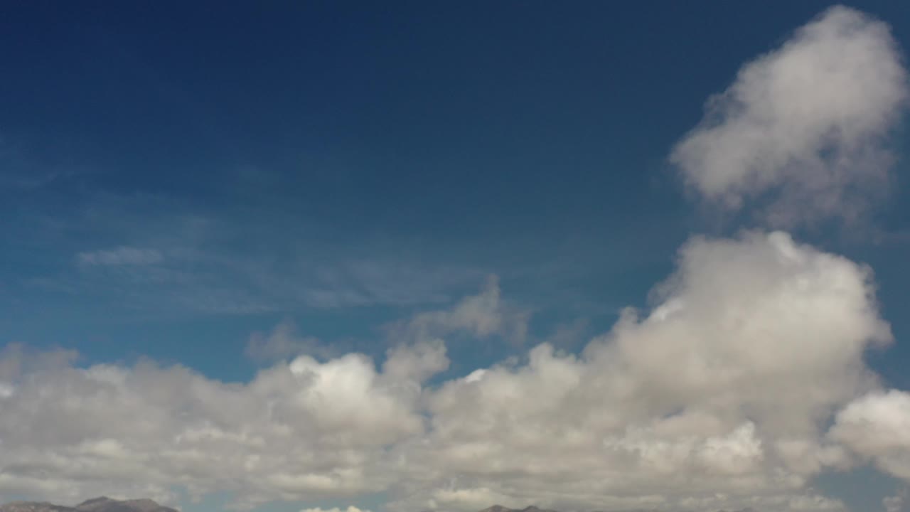 Large white clouds below a deep blue sky.