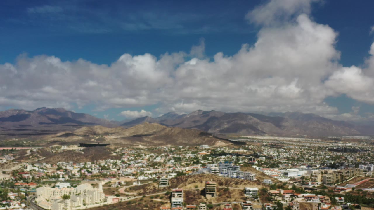 Wide city and mountain panorama with bright clouds over the horizon.