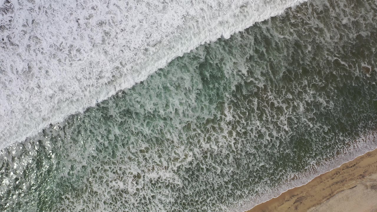 Aerial shoreline with dense foam and narrow beach