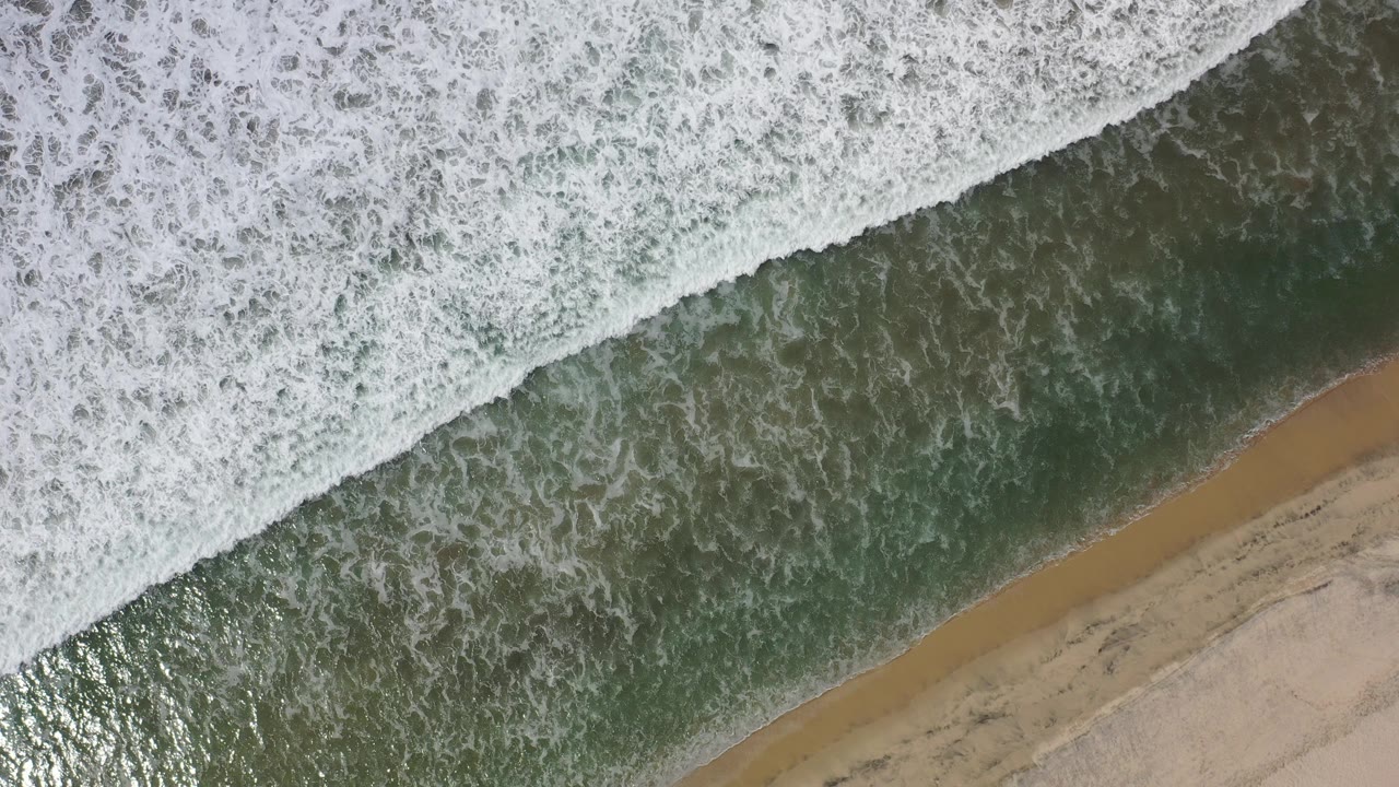 Overhead surf crossing a sandy shoreline