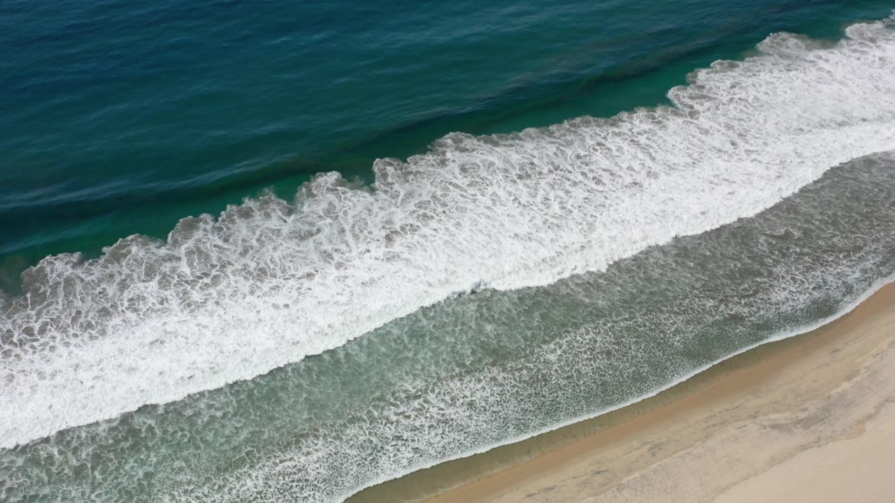 Overhead surf breaking onto a sandy beach