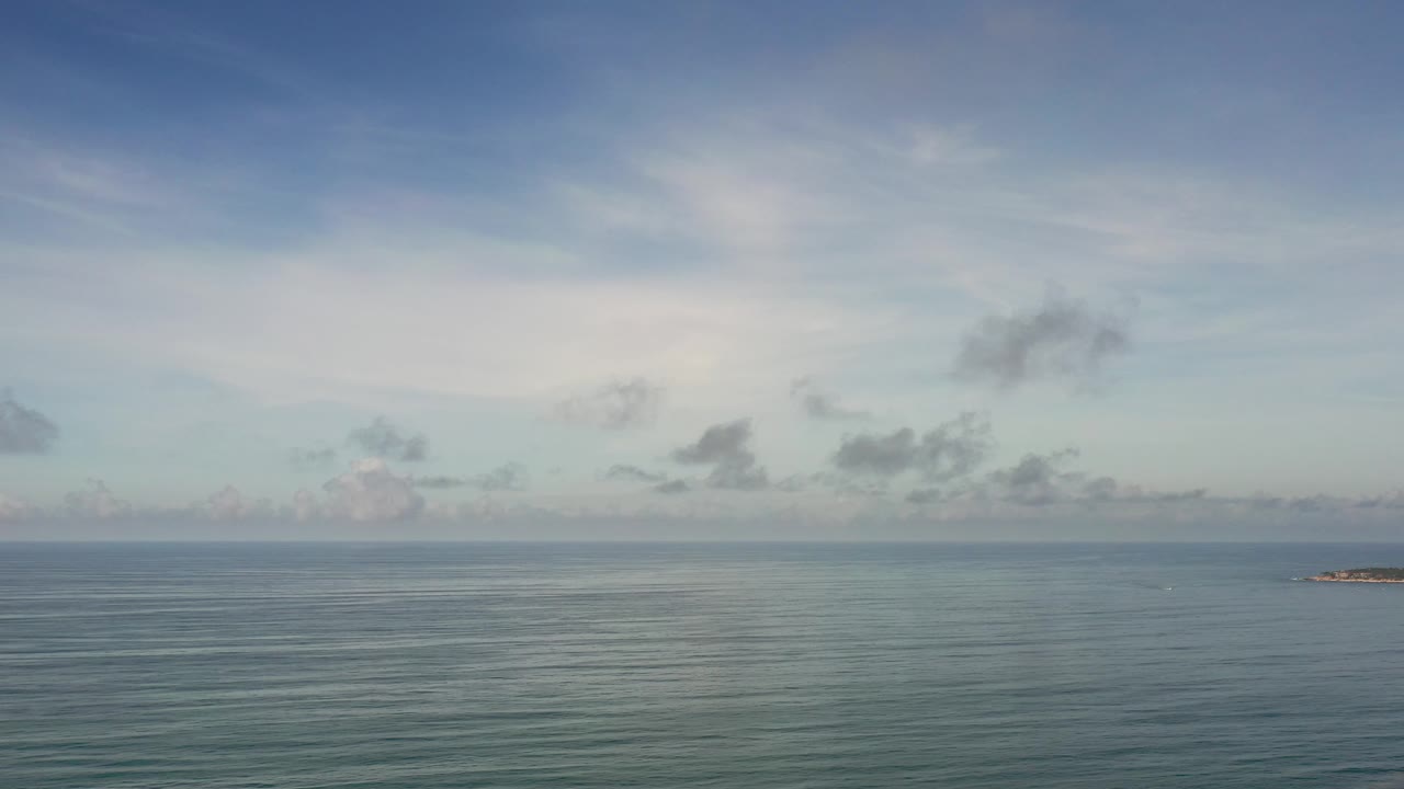 Calm sea horizon with scattered clouds
