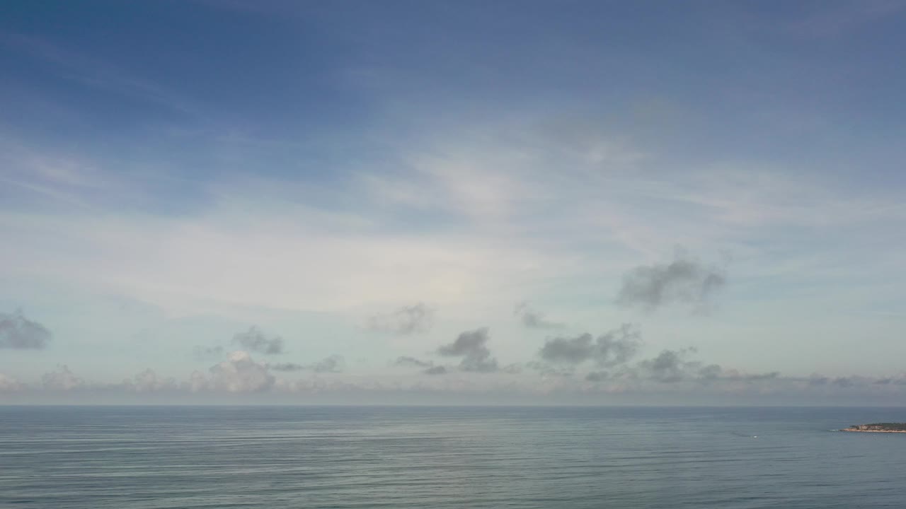 Open water and cloudy sky with a small rocky landform near the right edge.