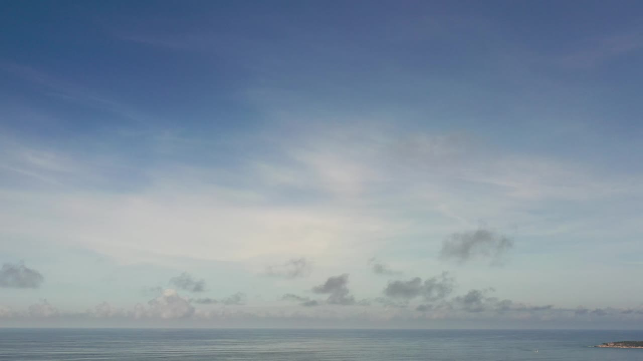 Wide sky with scattered clouds and a small distant landform