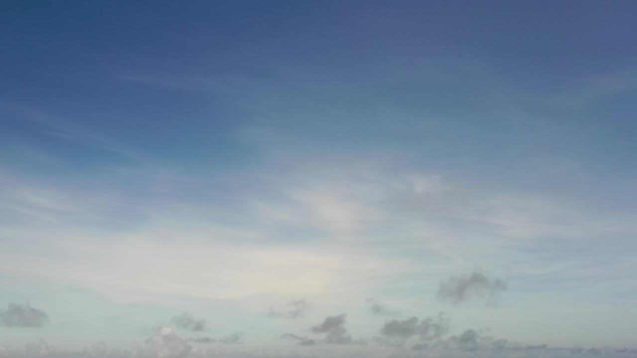 Blue sky with hazy white clouds and small darker clouds.