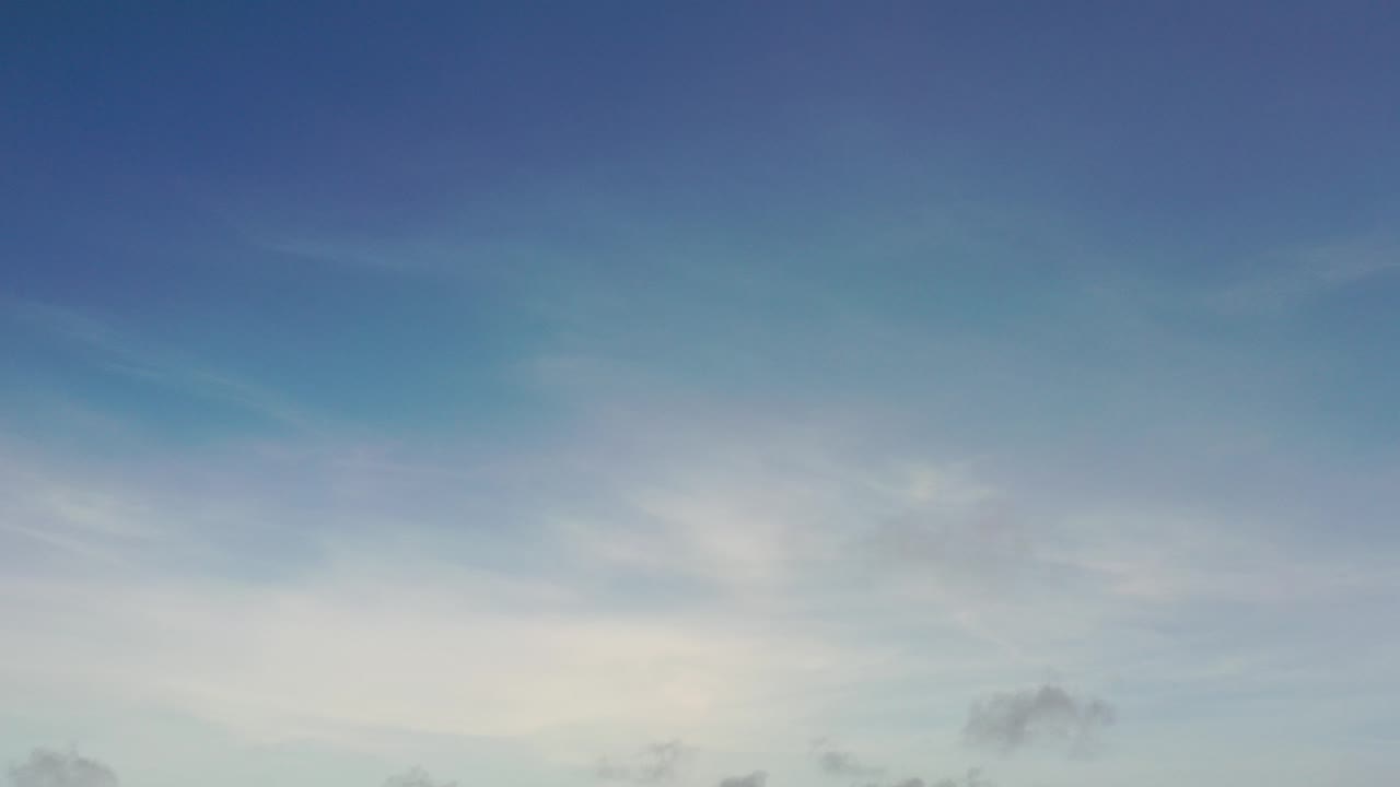 Opening frame of a Los Cabos sky view with deep blue upper sky, pale cloud streaks below, and no visible people.