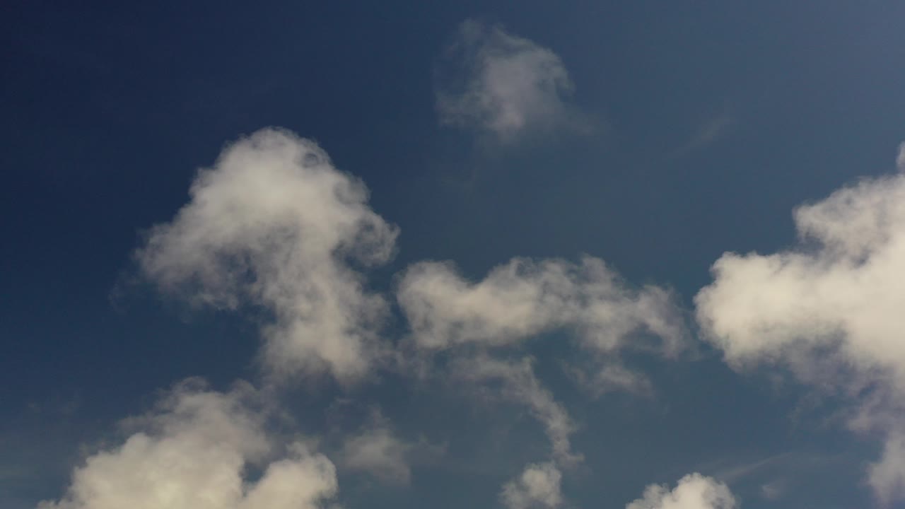 Opening frame of the Los Cabos clip with soft white clouds spread across a deep blue sky and no visible people.