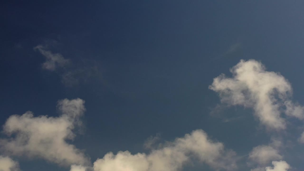 Los Cabos sky view with a large soft white cloud near the upper right and smaller cloud forms lower in frame, with no visible people.