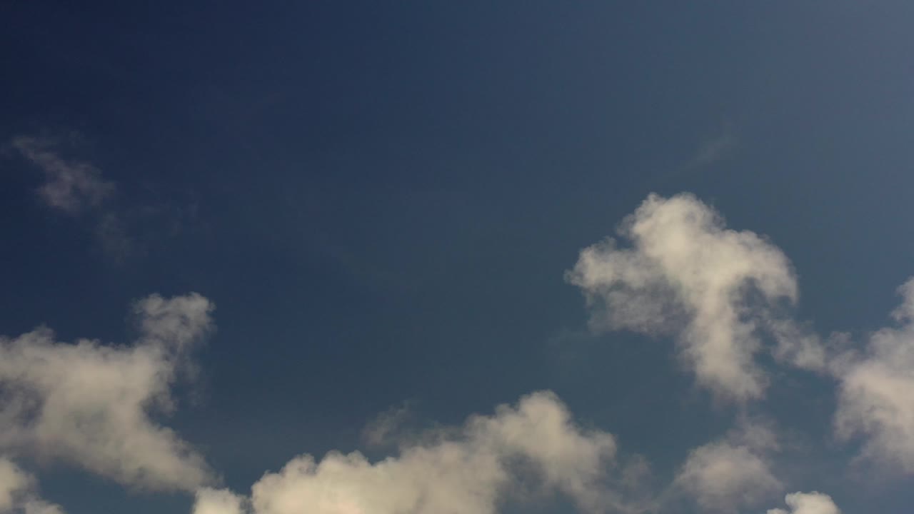 Puffy clouds below open blue sky