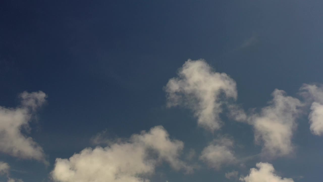 A larger white cloud shape appears near the upper left with smaller clouds across the Los Cabos sky, and no visible people.