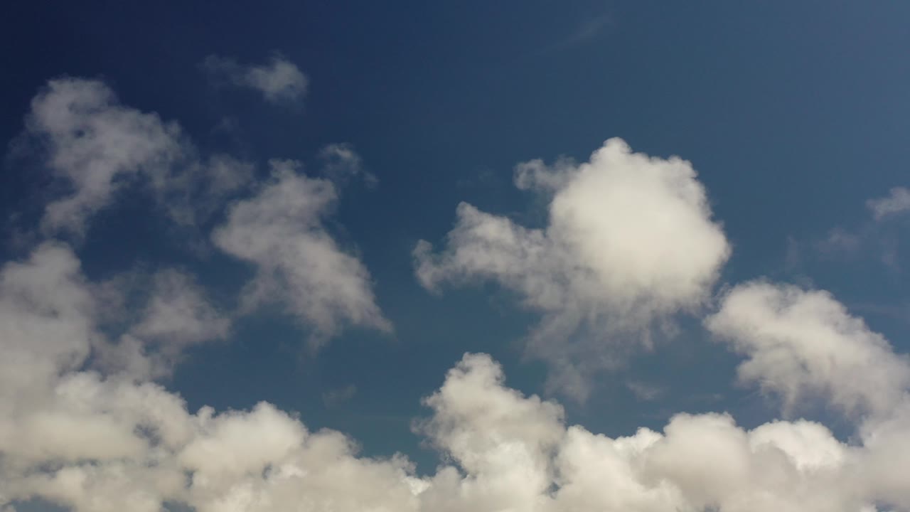 Puffy clouds against a dark blue sky.