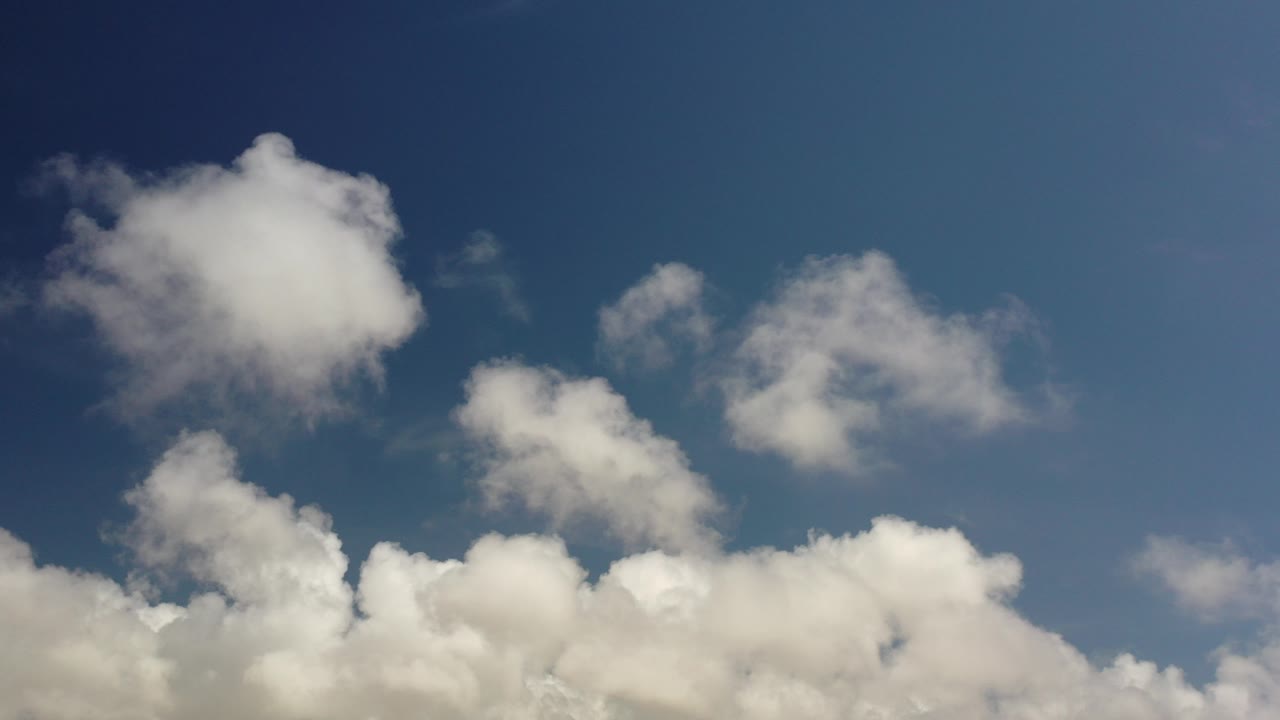 White clouds fill the lower edge and upper left of a blue Los Cabos sky, with no visible people or ground features.