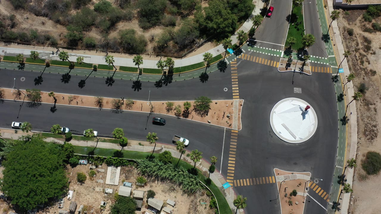 Overhead road junction with cars, crosswalks, sidewalks, and landscaped trees.