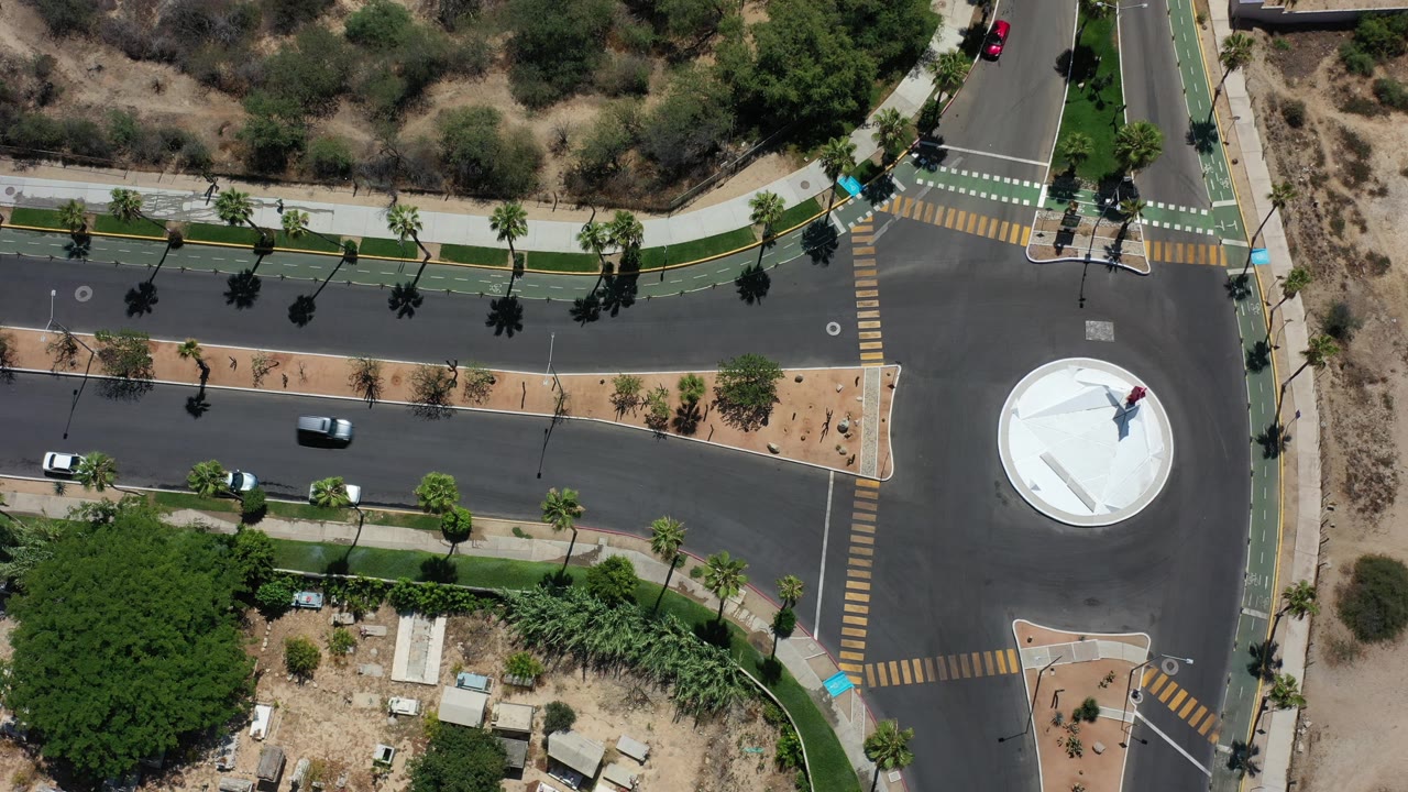 Top-down road scene with a car moving near the roundabout and marked bike lanes.