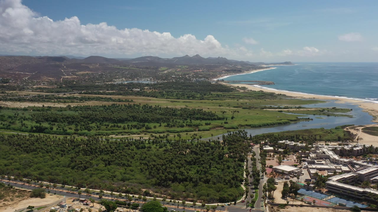 Aerial view of coast, lagoon, green vegetation, hills, and ocean.
