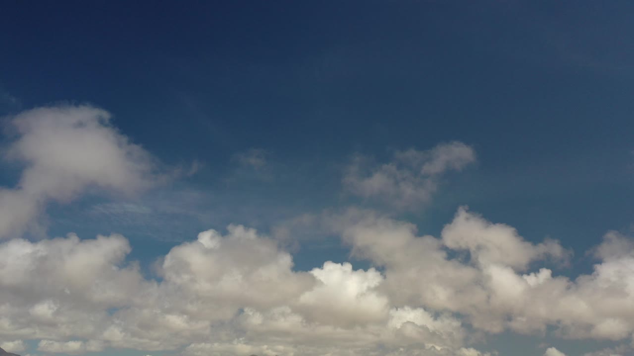 Blue sky with scattered white clouds along the lower frame.