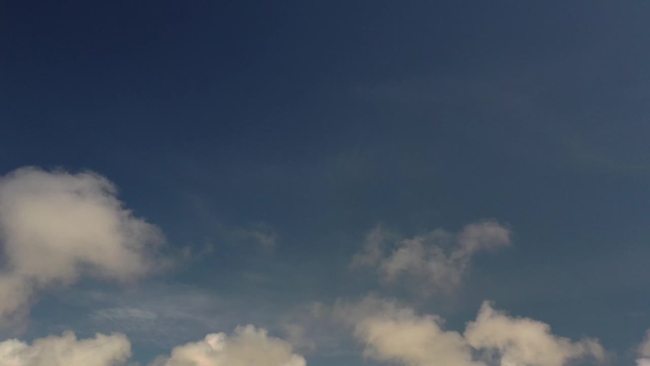 Los Cabos sky frame with a soft pale cloud near the upper left, smaller wisps through the center, heavier clouds at the bottom, and no visible people.