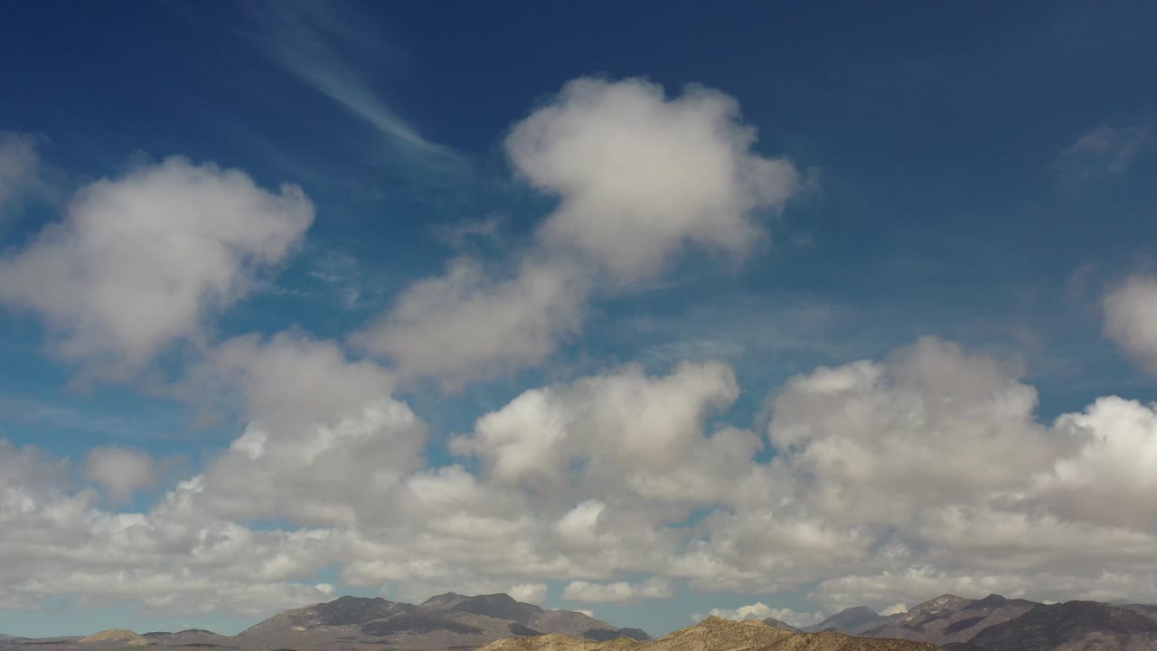 Cloudy blue sky over distant brown mountains.