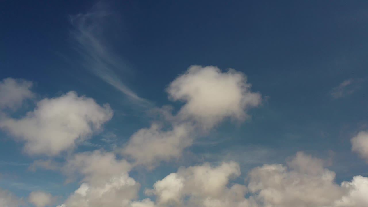 Blue Los Cabos sky with a rounded white cloud near the upper right, lower cloud banks, and no visible people.