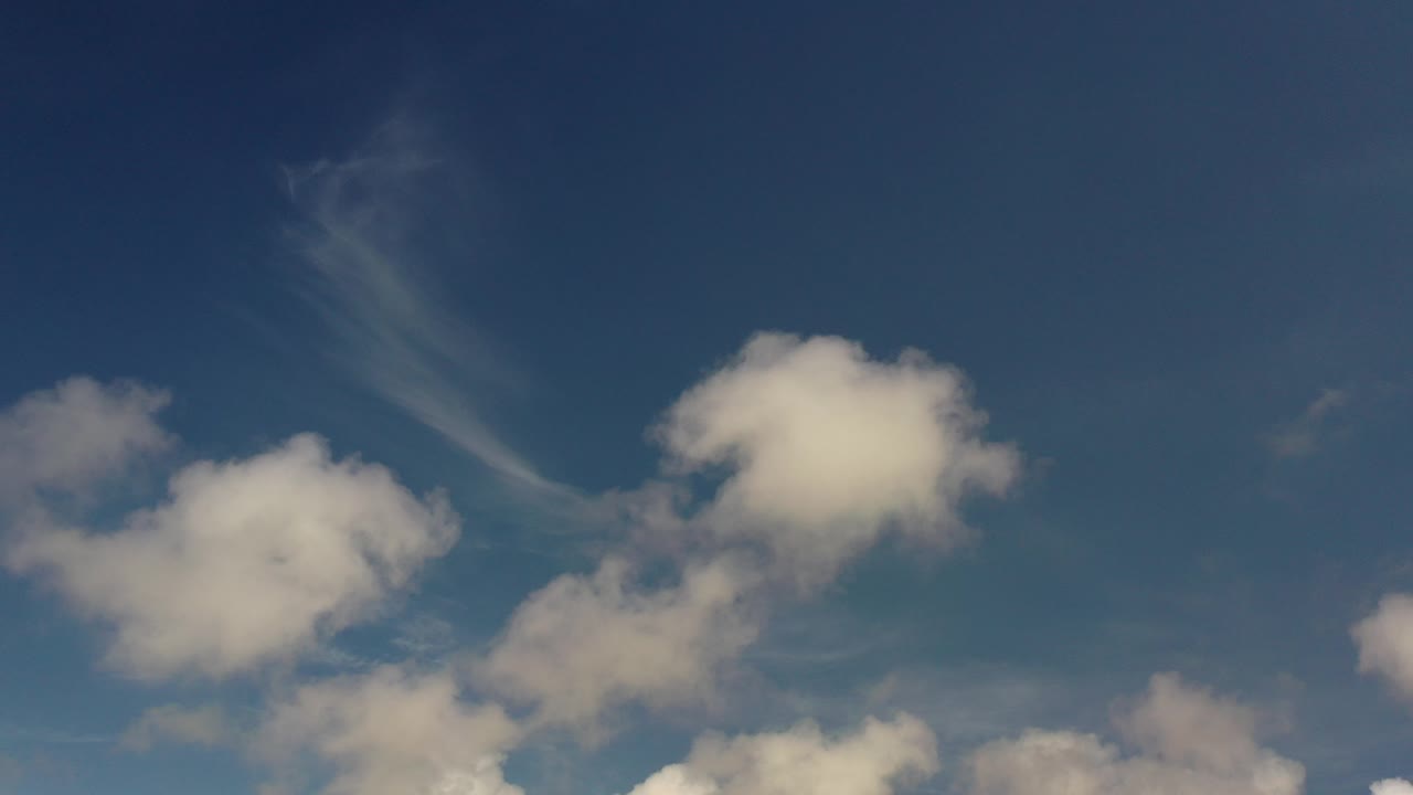 Opening frame of the Los Cabos, Mexico clip showing blue sky, soft puffy white clouds, and a faint diagonal streaked cloud, with no visible people.