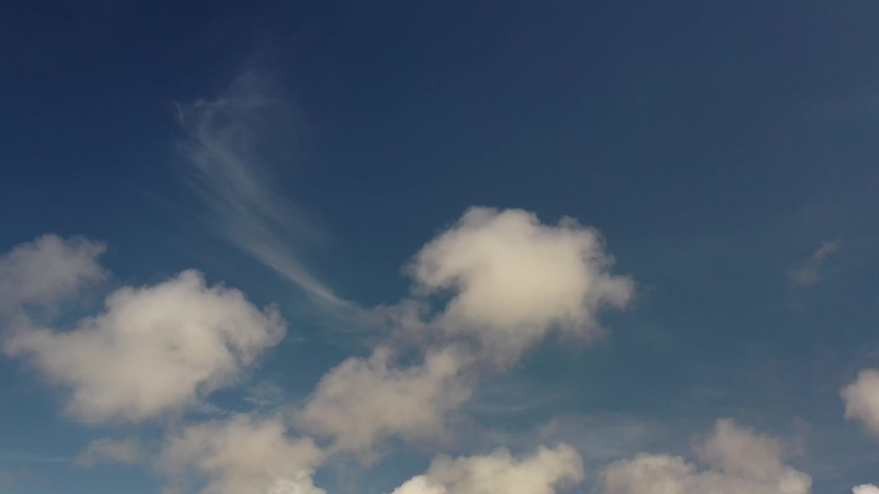 Second frame from Los Cabos, Mexico showing the same open blue sky with rounded white clouds more centered in the view and no visible people.