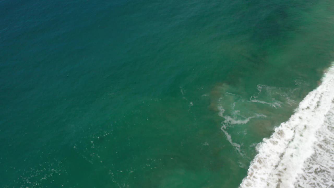 Green ocean surface with white foam breaking at the far right.