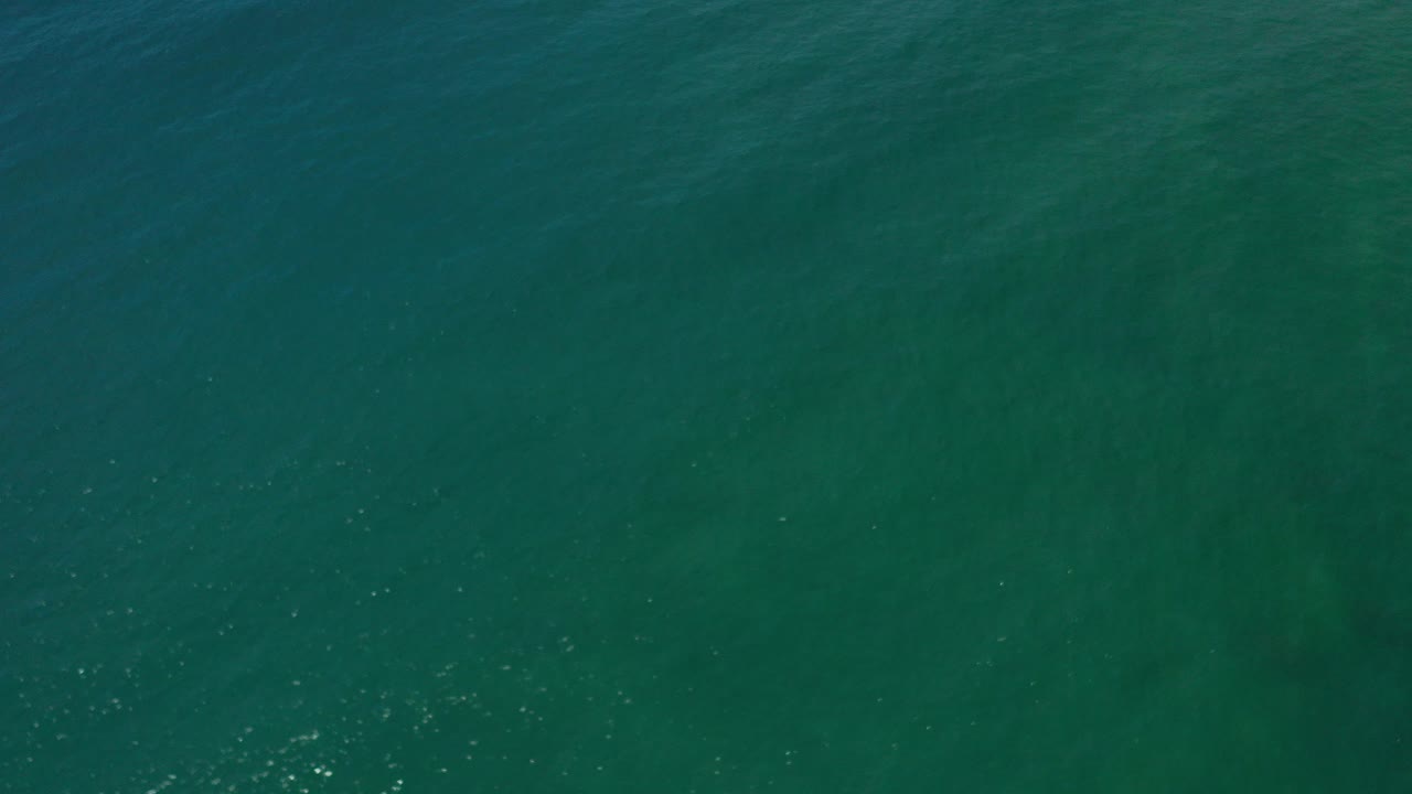 Blue-green ocean water in Los Cabos viewed from above at the opening moment, with faint ripples and no visible people.