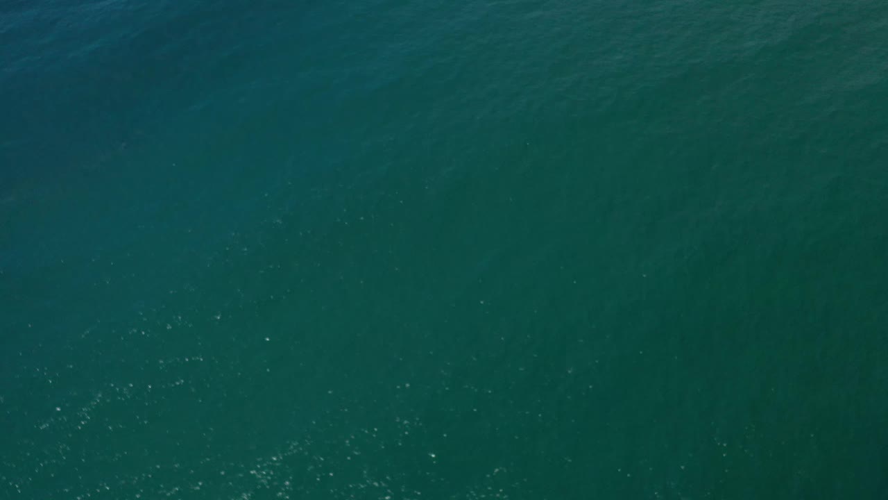 Overhead Los Cabos water surface with fine ripple lines, slightly brighter scattered reflections, and no visible people, boats, or shoreline.