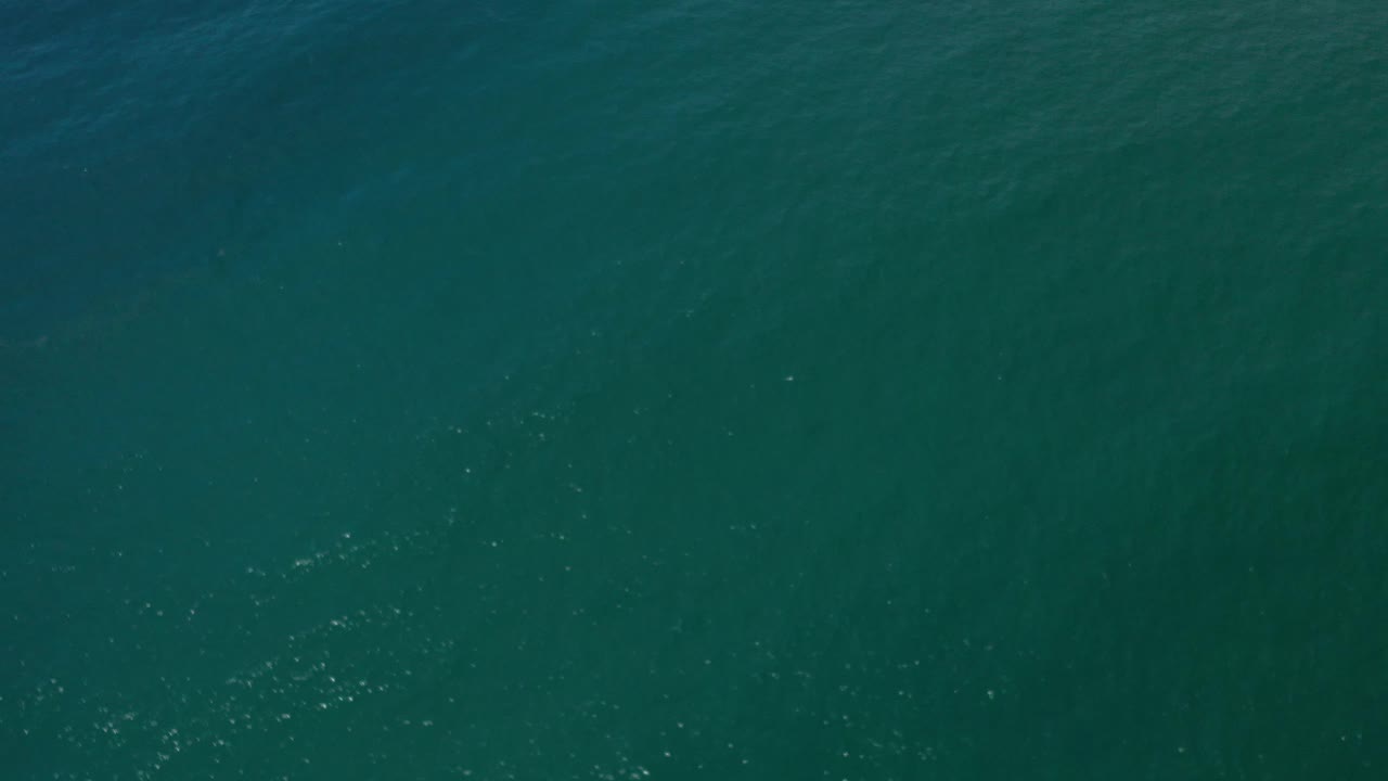 Green ocean water seen from above with soft darker bands and tiny highlights.