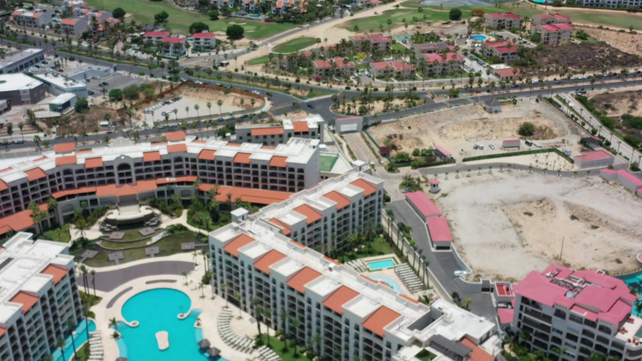 Aerial view of resort buildings, pools, roads, and green land.