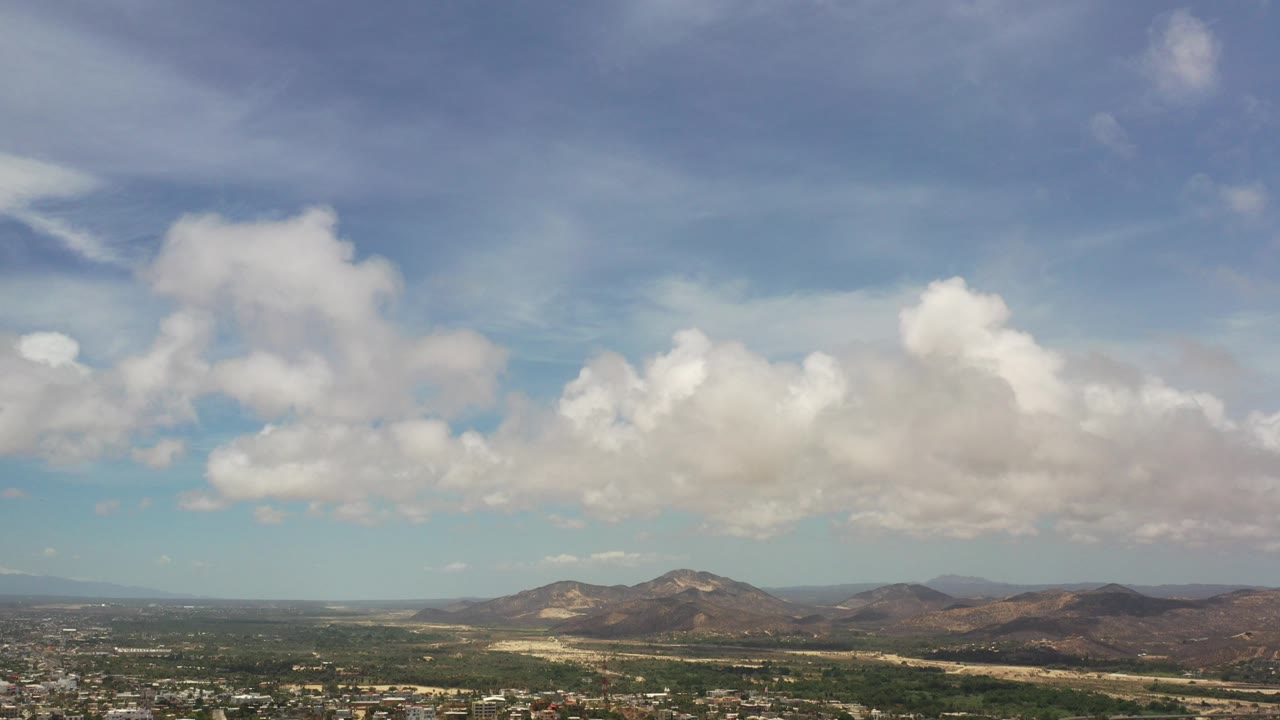 Cumulus clouds over low mountains and distant landscape.