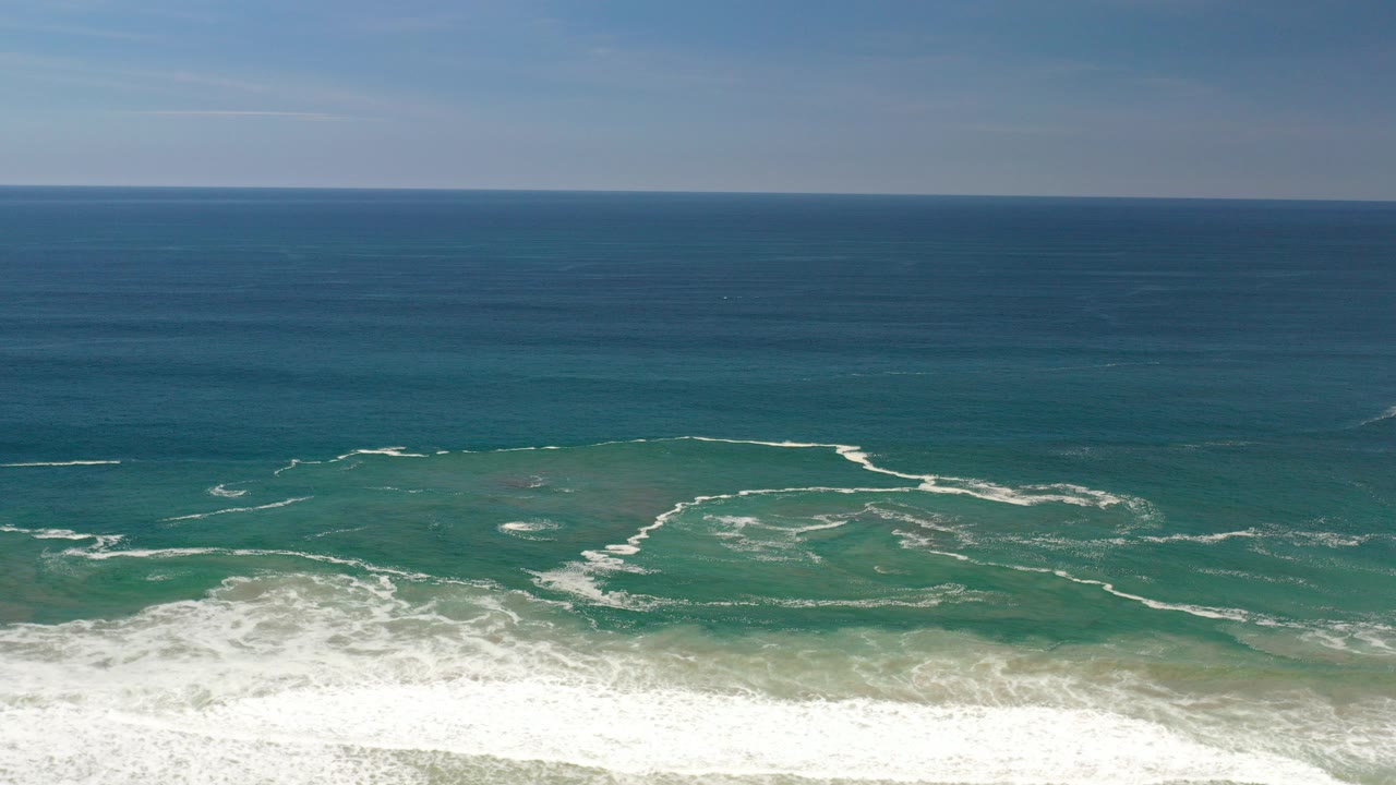 Turquoise ocean with white surf lines below a blue horizon
