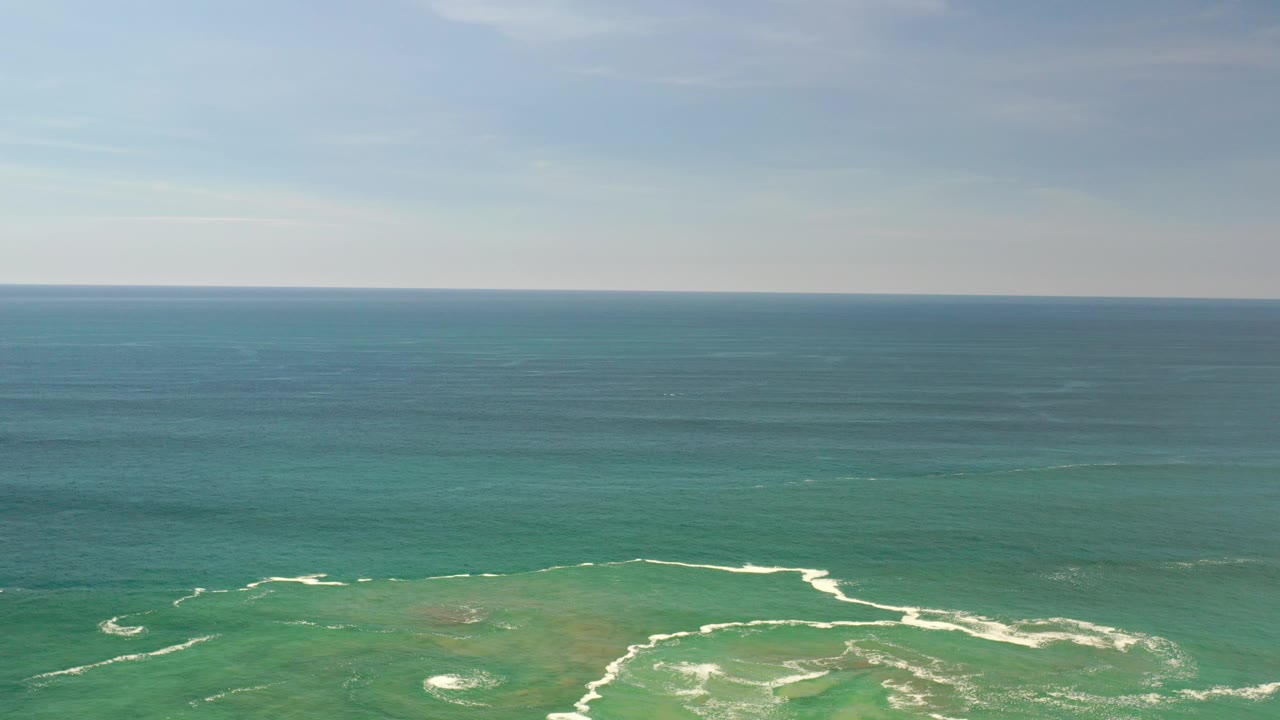 Blue-green ocean panorama with small white wave lines near the lower frame.