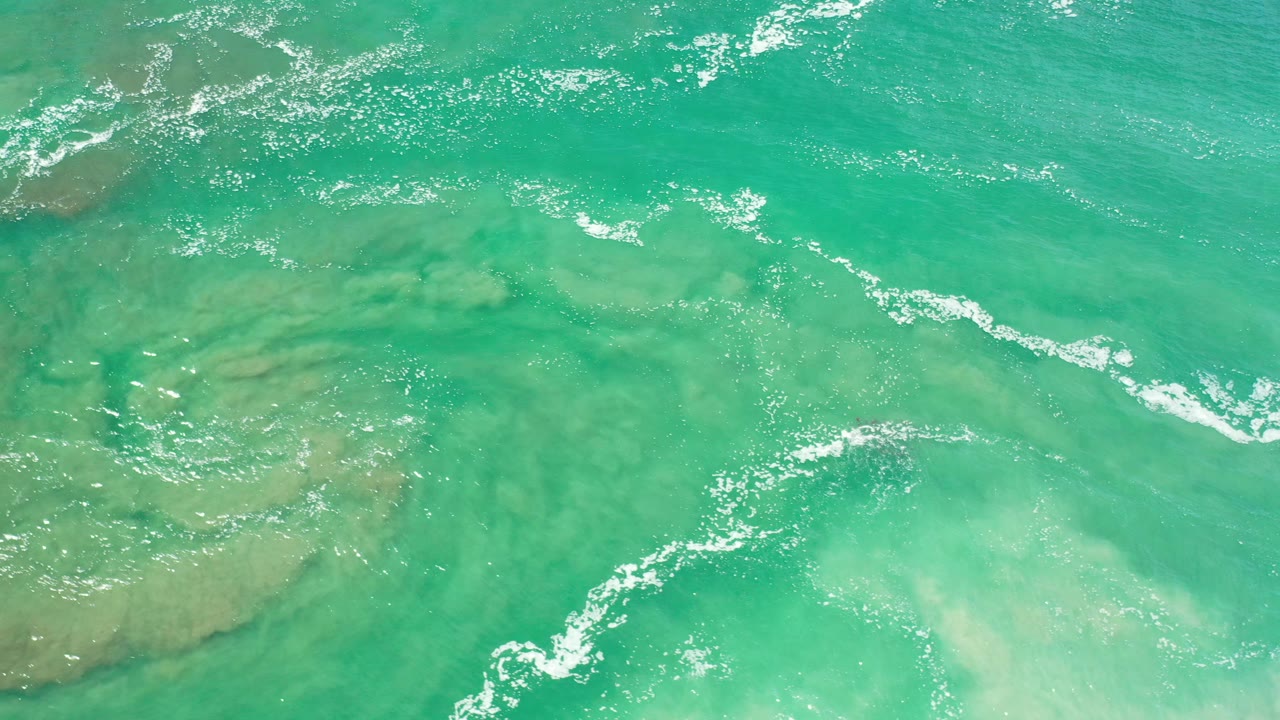 Clear turquoise water with white ripple foam near the upper edge.
