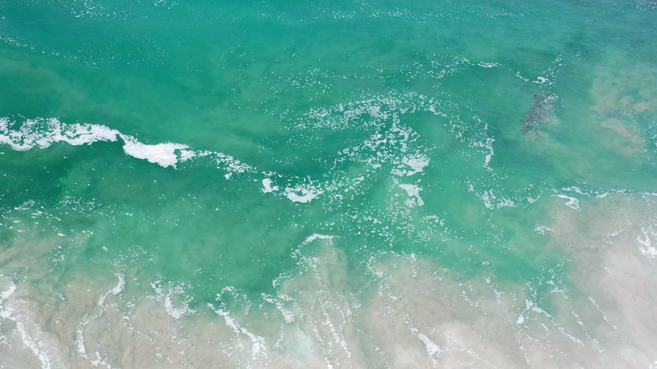 Overhead view of turquoise ocean water at Los Cabos, Mexico, with a broken white surf line near the lower edge and no visible people.