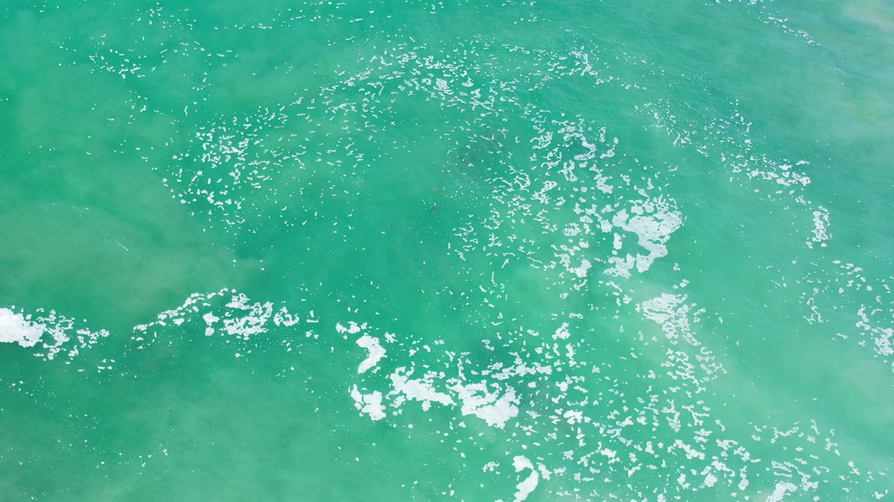 Overhead turquoise ocean with white foam patches