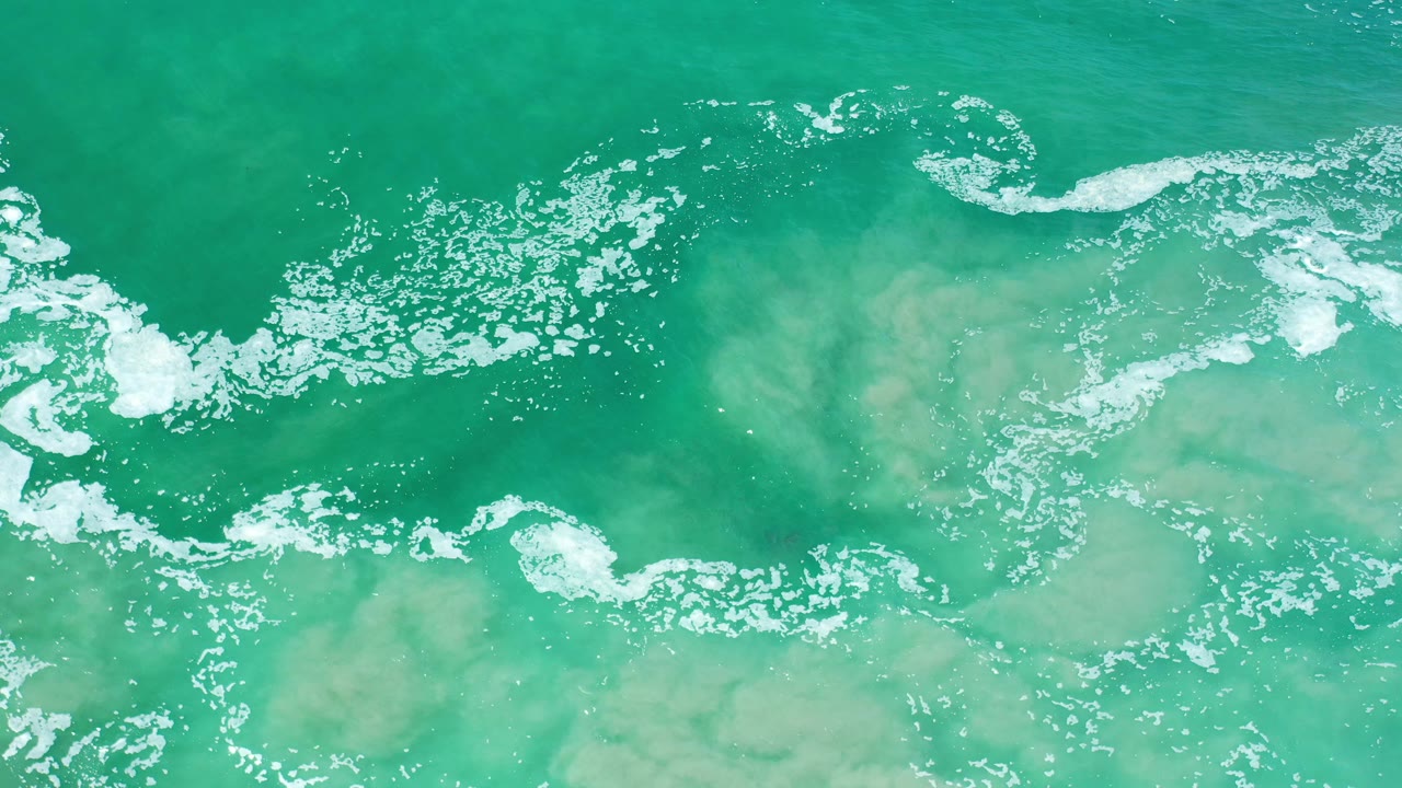 Murky aqua water with broken white foam patches.