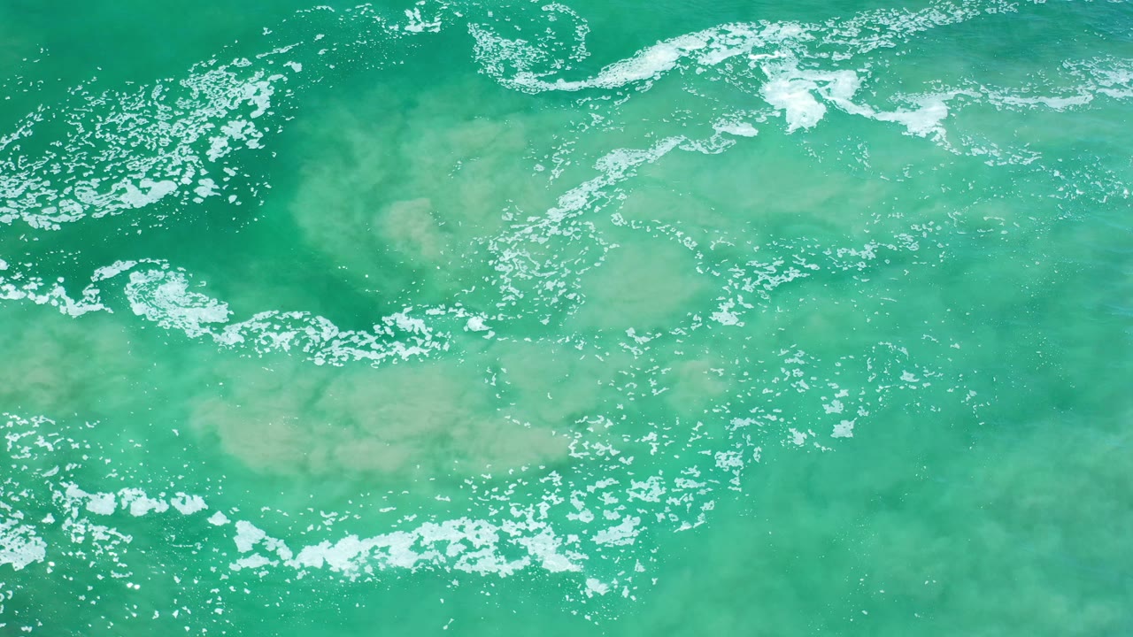 Turquoise water with broken foam and pale underwater color variations.