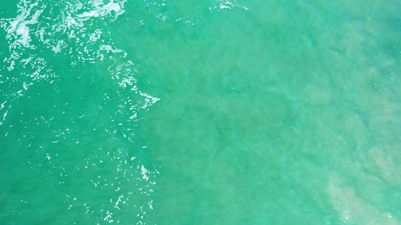 Green ocean surface with small bright ripples near the upper left.