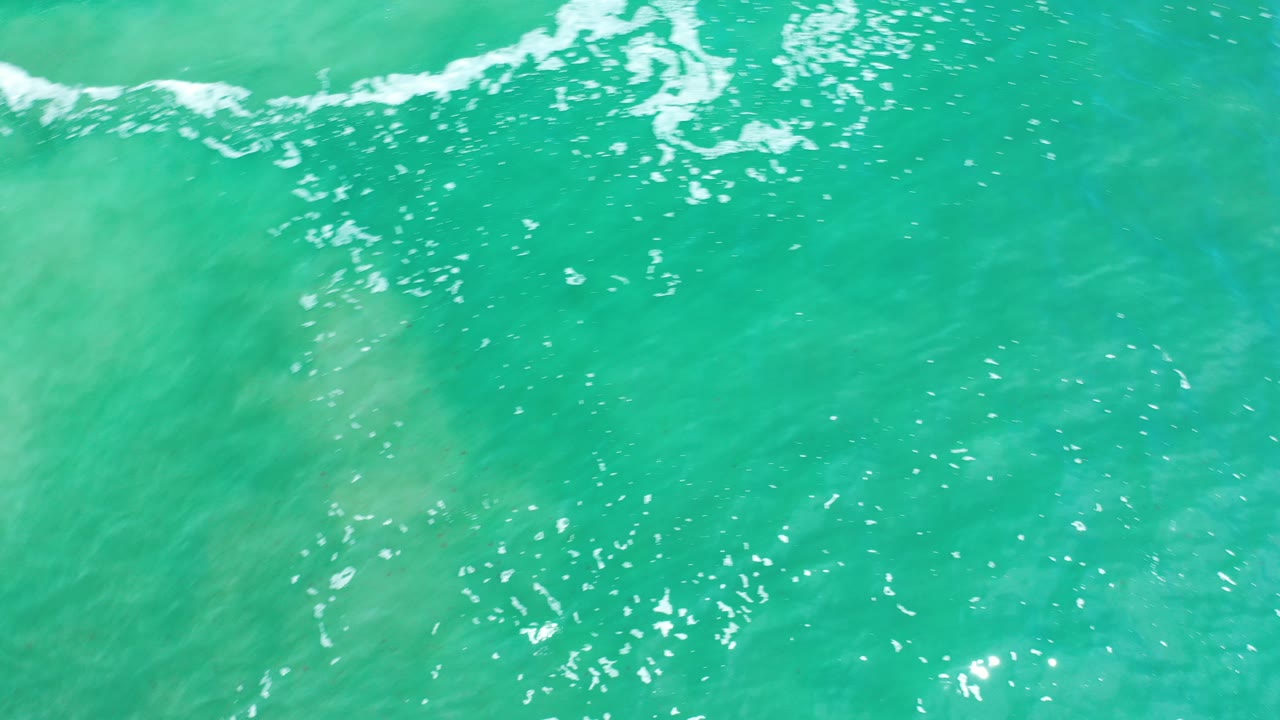 Turquoise ocean water with a white foam line near the top edge.