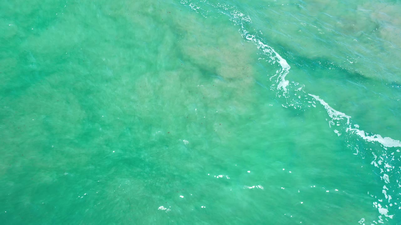 Turquoise water with white foam entering near the right edge.