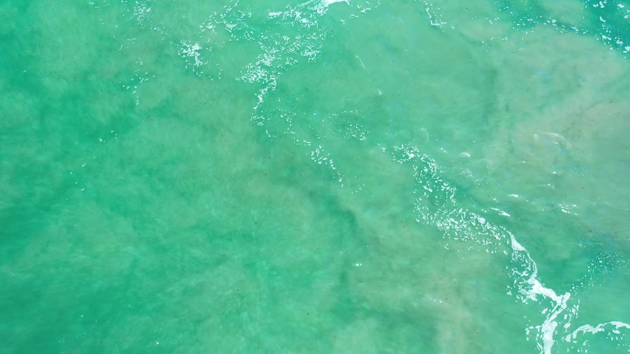 Green-blue water with cloudy rock texture and broken white foam.