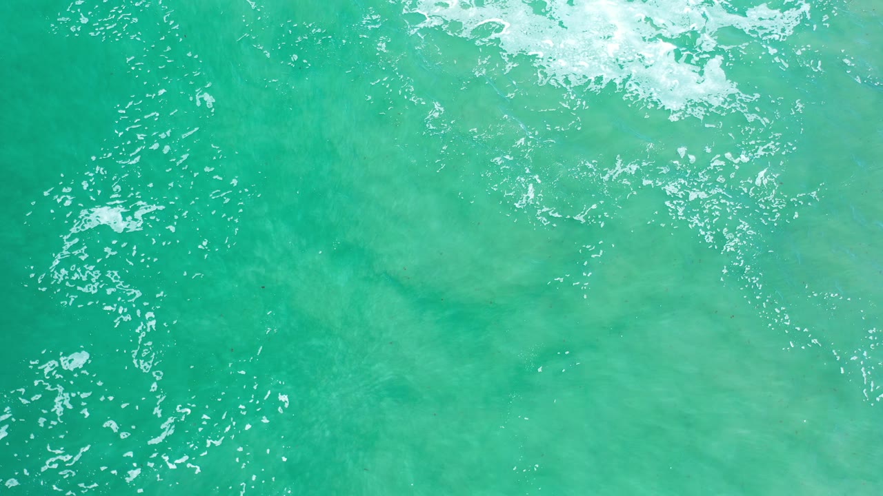 Clear green-blue ocean water with white foam across the top.