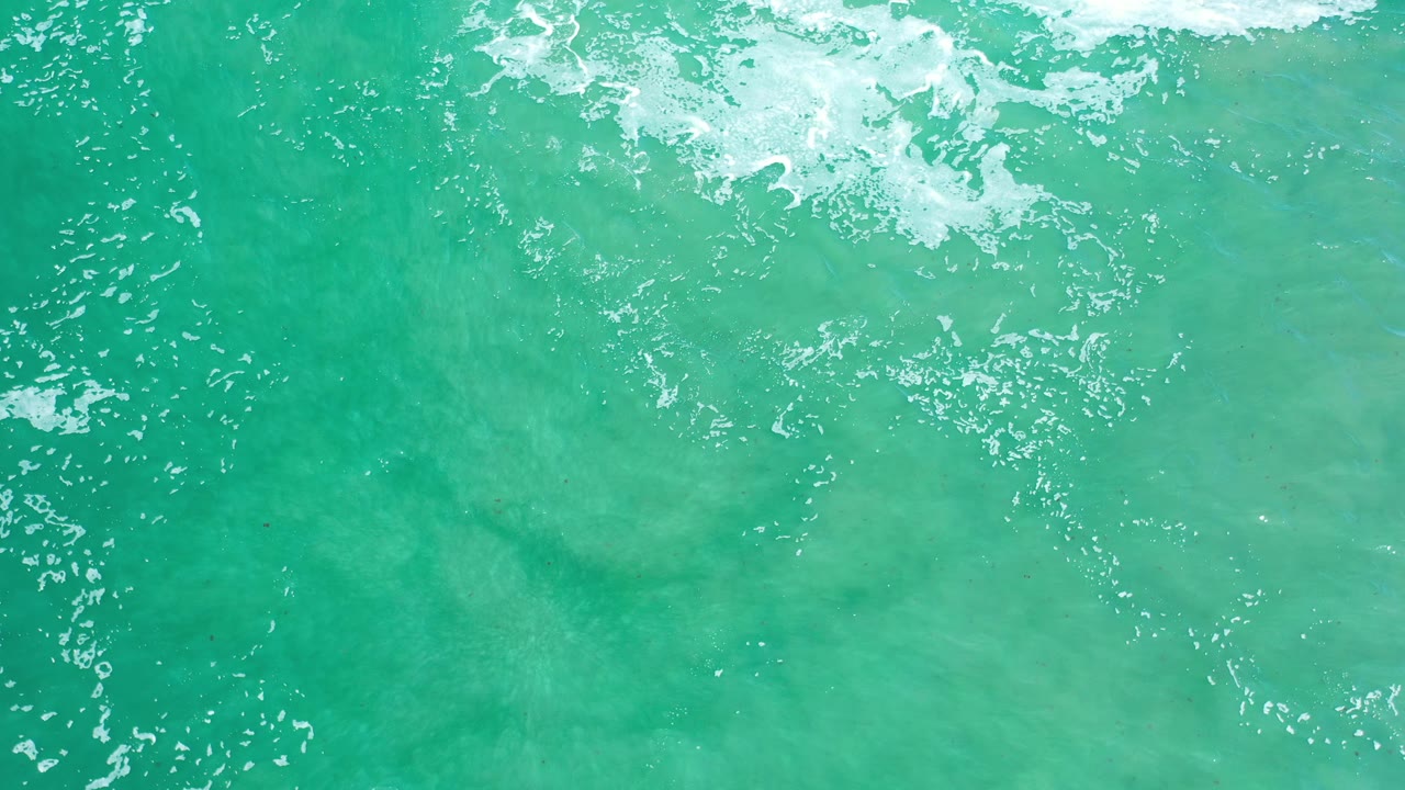 Turquoise water seen from above with scattered white wave foam