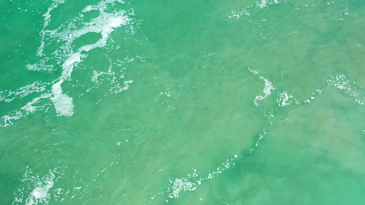 Green ocean water with white foam streaks viewed from above.